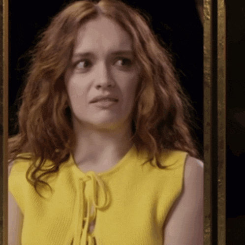 a woman with red hair wearing a yellow top