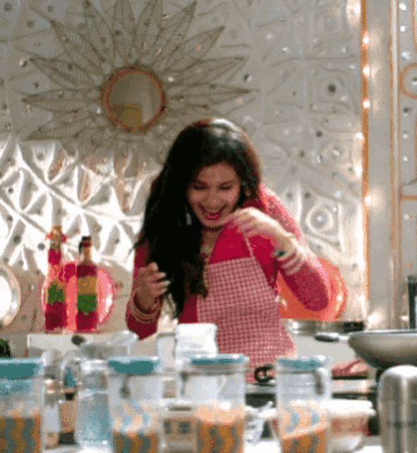 a woman in a pink apron stands in front of a mirror