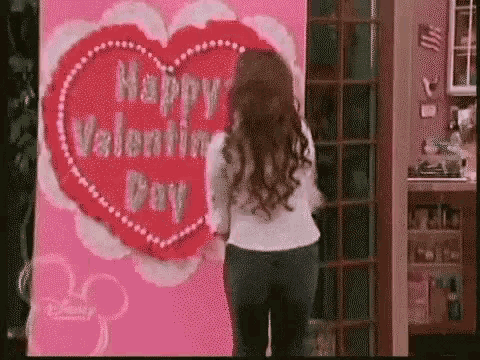 a woman is standing in front of a happy valentine 's day card .
