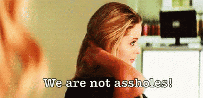 a woman is sitting in front of a computer with the words `` we are not assholes '' written above her .