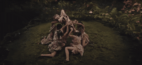 a group of women sitting in the grass with one holding a baby