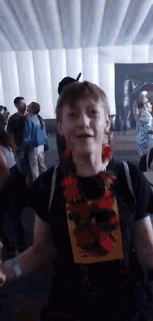 a man wearing a lei and a black shirt is standing in a crowd .
