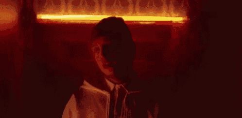 a close up of a person 's face in the dark with a red light behind them .