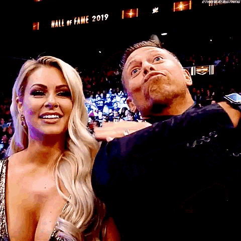 a man and a woman are posing for a picture in front of a sign that says hall of fame 2019 .