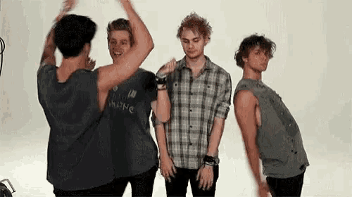 a group of young men are standing next to each other in a room and dancing .