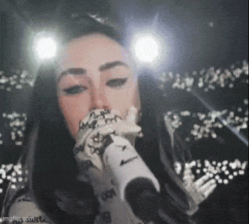 a woman is singing into a microphone in front of a crowd of people .