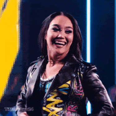 a woman wearing a leather jacket with graffiti on it laughs