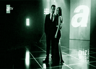 a man and a woman are standing next to each other on a stage in a dark room .