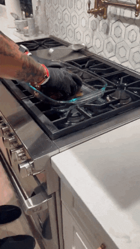 a person cooking on a stove with a tray of food on it