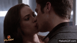a man and a woman kissing with the flash logo in the background
