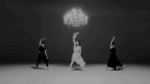 a black and white photo of a person dancing under a chandelier .