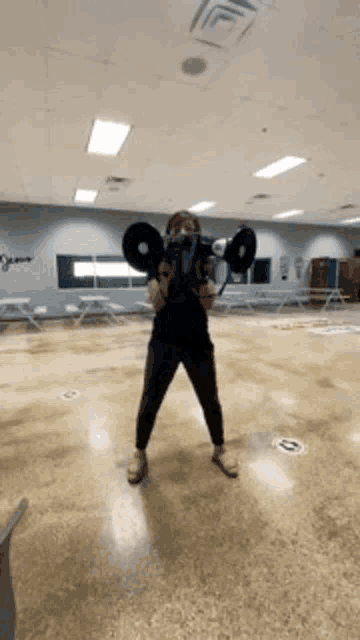 a woman is holding a megaphone in front of her face in a gym .