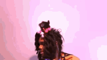 a person with a cat on their head against a pink background