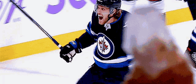a hockey player wearing a jersey with a maple leaf on it celebrates a goal