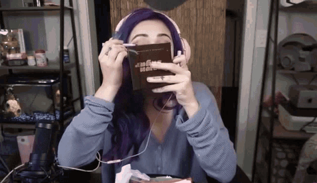 a woman with purple hair is holding a box that says jasmine dust in front of her face