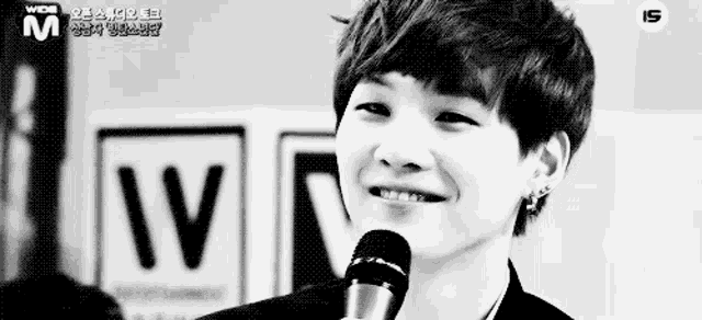 a young man is smiling in front of a microphone .