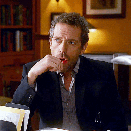 a man in a suit is sitting at a desk with his hand on his chin