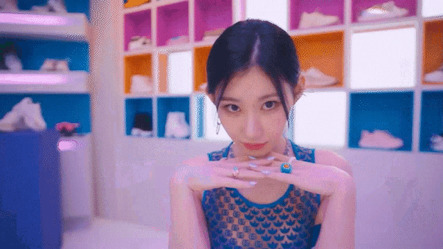 a woman in a blue dress with a blue ring on her finger looks at the camera .
