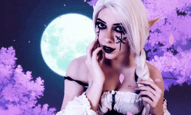 a woman with white hair and black makeup stands in front of a full moon and purple flowers