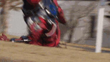 a man in a red and silver armor is kneeling down in the dirt .