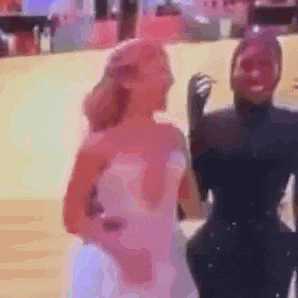 a couple of women standing next to each other on a red carpet . one of the women is wearing a white dress .