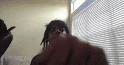 a man with dreadlocks is standing in front of a window .