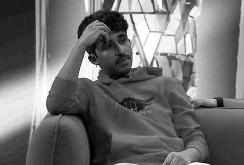 a man wearing a hollister sweatshirt sits in a chair