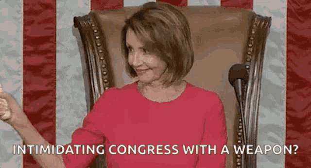 a woman in a red dress is sitting in a chair in front of a microphone and giving a thumbs up .