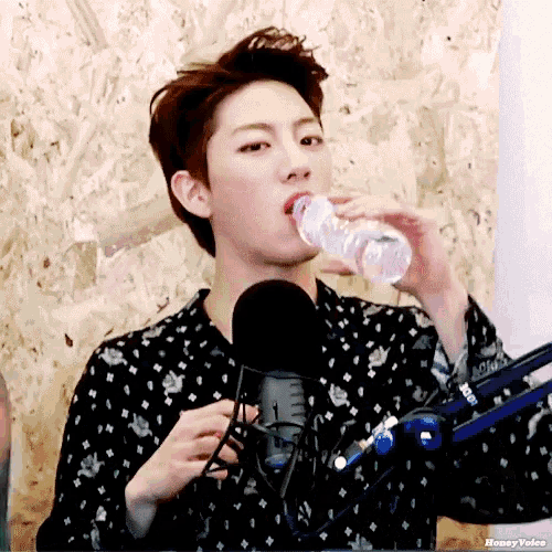 a young man drinking water from a bottle in front of a microphone with the words honey voice below him