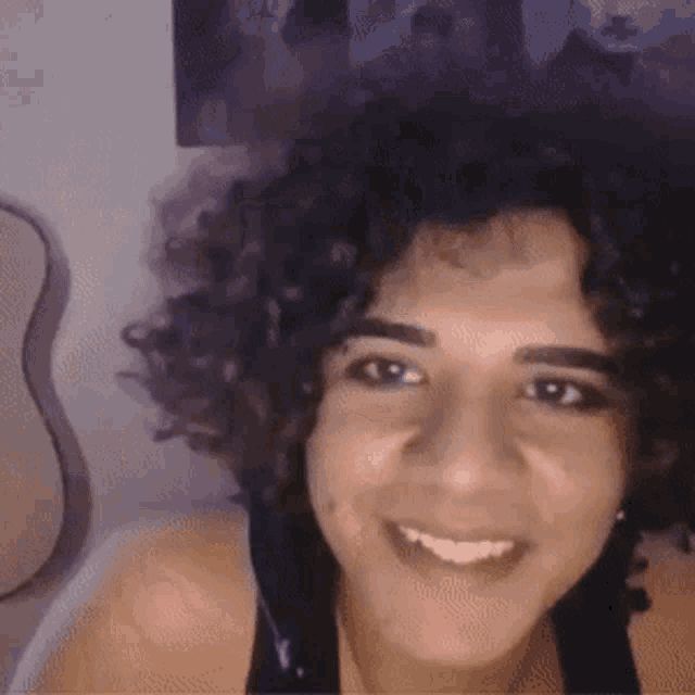 a woman with curly hair is smiling and looking at the camera