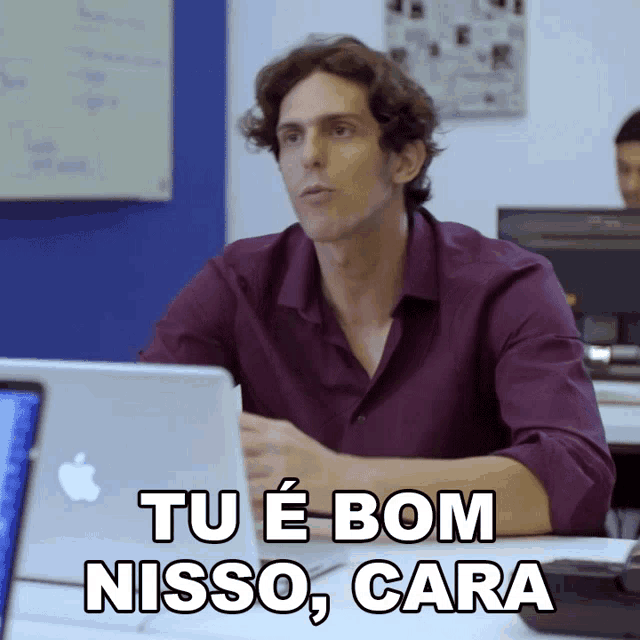 a man sits at a desk with an apple laptop and says tu e bom nisso cara