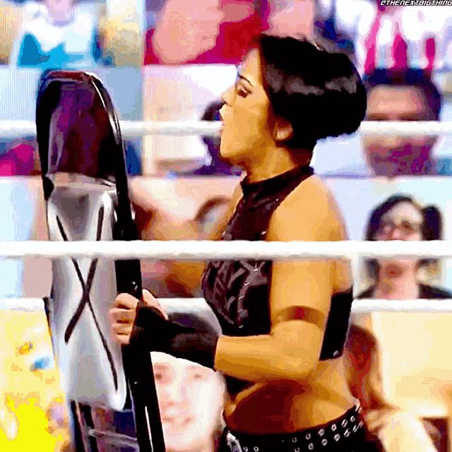 a woman in a wrestling ring is holding a shield with the letters x on it