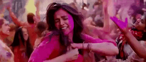a woman in a pink dress is dancing in a crowd of people .