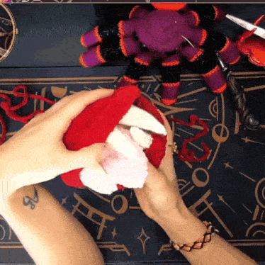 a person with a tattoo on their arm is holding a stuffed animal in their hands
