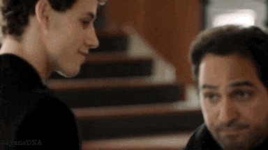 two men are standing next to each other in front of stairs and looking at each other .