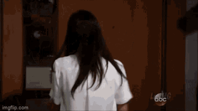 a woman in a white shirt is standing in front of a door that says abc