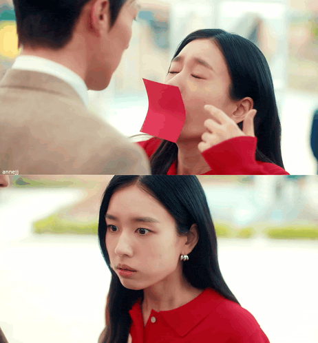 a woman in a red shirt has a piece of paper in her mouth