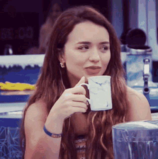 a woman drinking from a white mug with a bird on it in front of a sign that says 8:30