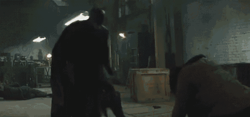 a man in a cape is kneeling down in a dark room .