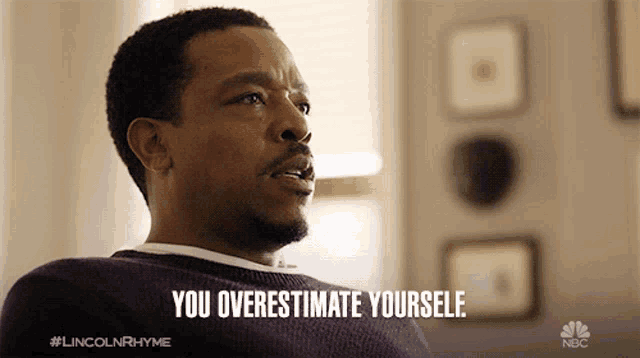 a man is sitting on a couch and says you overestimate yourself