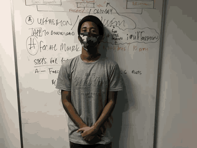 a man wearing a mask stands in front of a whiteboard that says " upfashion "