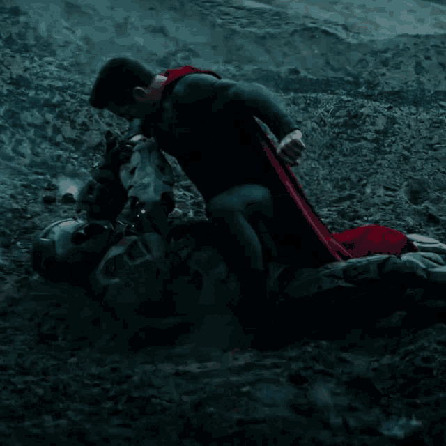 a man in a superman costume is kneeling down next to another man