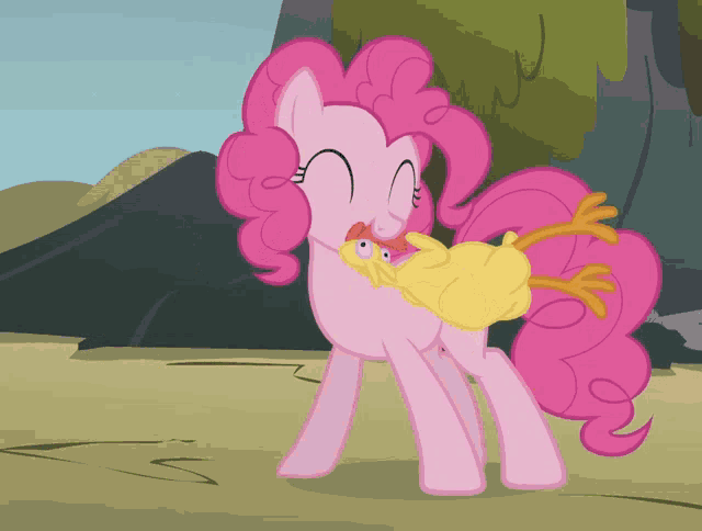 a pink pony holding a yellow chicken in her mouth