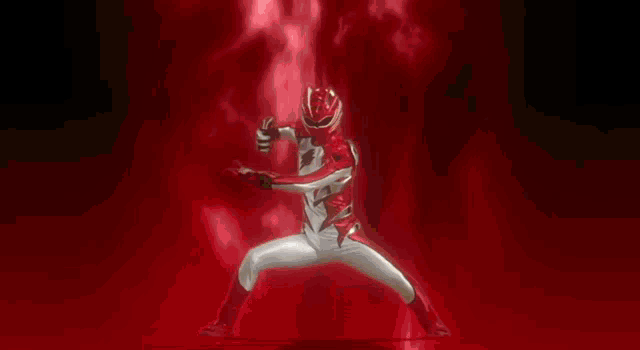 a man in a red and white superhero costume is standing in front of a red fire .