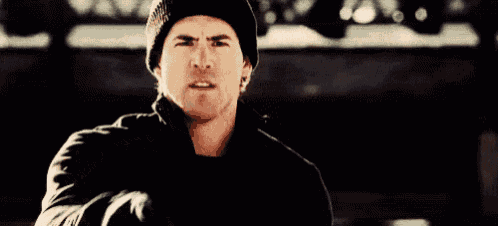 a man wearing a black hat and gloves is pointing