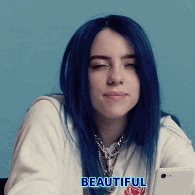 billie eilish with blue hair is holding a cell phone in her hand .