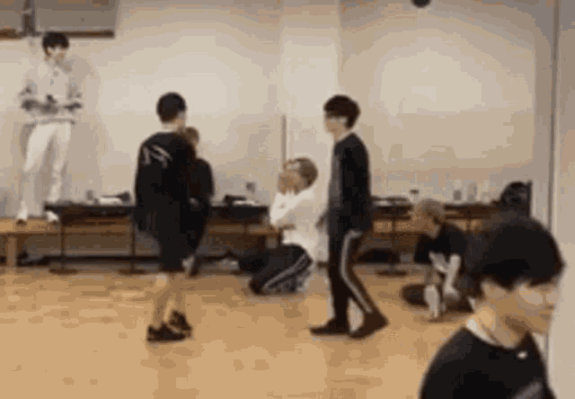 a group of young men are dancing in a room with a wooden floor .