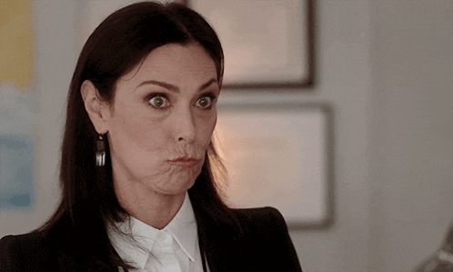 a woman in a suit making a funny face with her mouth open