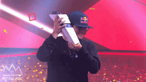 a man wearing a redbull hat holds a trophy