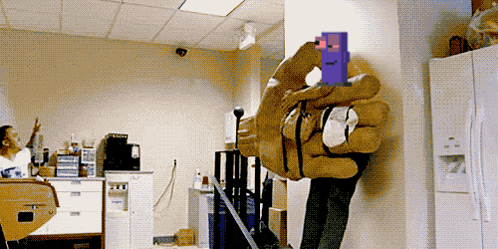 a person holding a giant hand with a pixelated face on it in a room
